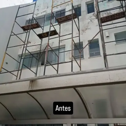 Fachada de prédio de três andares antes da reforma, manchada e com andaime
