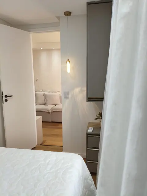Quarto com cama de casal, luminária pendente e cortina