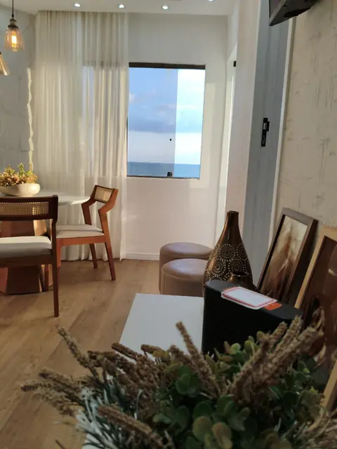 Mesa de jantar com cadeiras de madeira e janela com vista para o mar